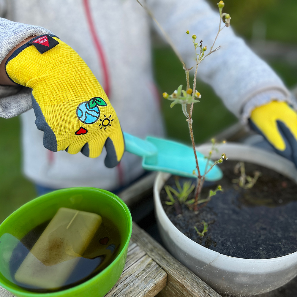 Kinderhandschuh aus 15G Polyester, Latexschaum, Kat I »KIDS 4« gelb schwarz, Anwendungsbild bei Gartenarbeiten.