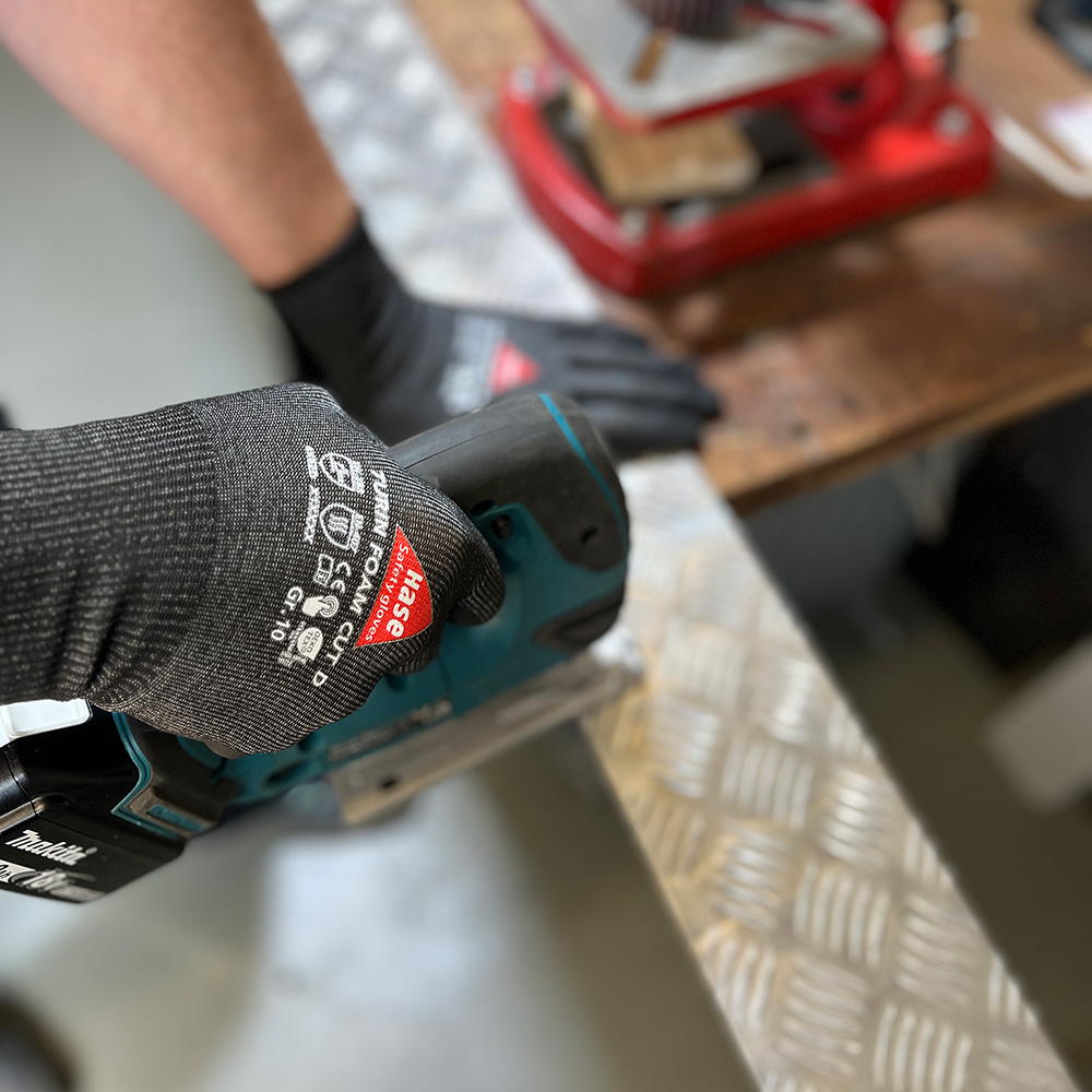 Schnittschutzhandschuh aus 15G HPPE, Nitrilschaum, CUT D »Turin Foam Cut D« schwarz, Anwendungsbild bei Metallarbeiten.