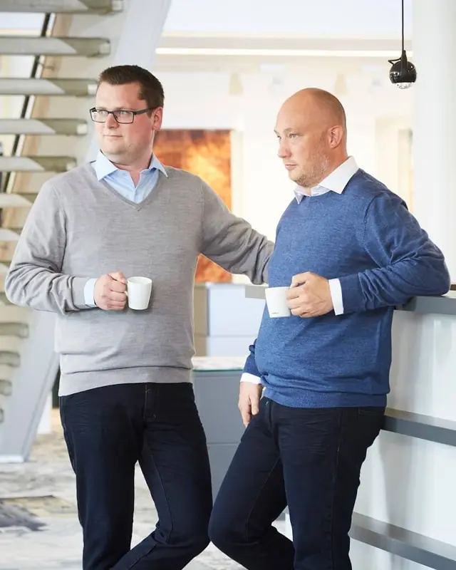 Zwei Männer in Hemd und Strickpullover in einer Bürolobby