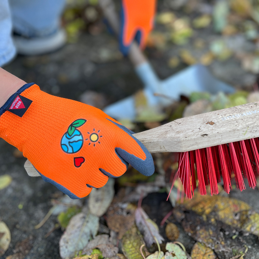 Kinderhandschuh aus 15G Polyester, Latexschaum, Kat I »KIDS 5« orange schwarz, Anwendungsbild bei Gartenarbeiten.