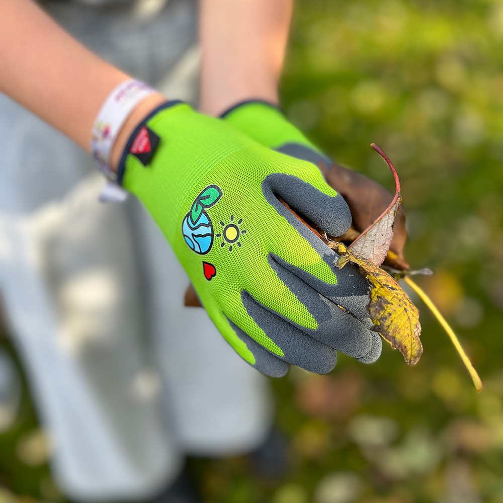 Kinderhandschuh aus 15G Polyester, Latexschaum, Kat I »KIDS 3« grün schwarz, Anwendungsbild bei Gartenarbeiten.